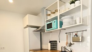 Una cocina moderna con armarios blancos, encimera de madera, microondas integrado y pileta de acero inoxidable.