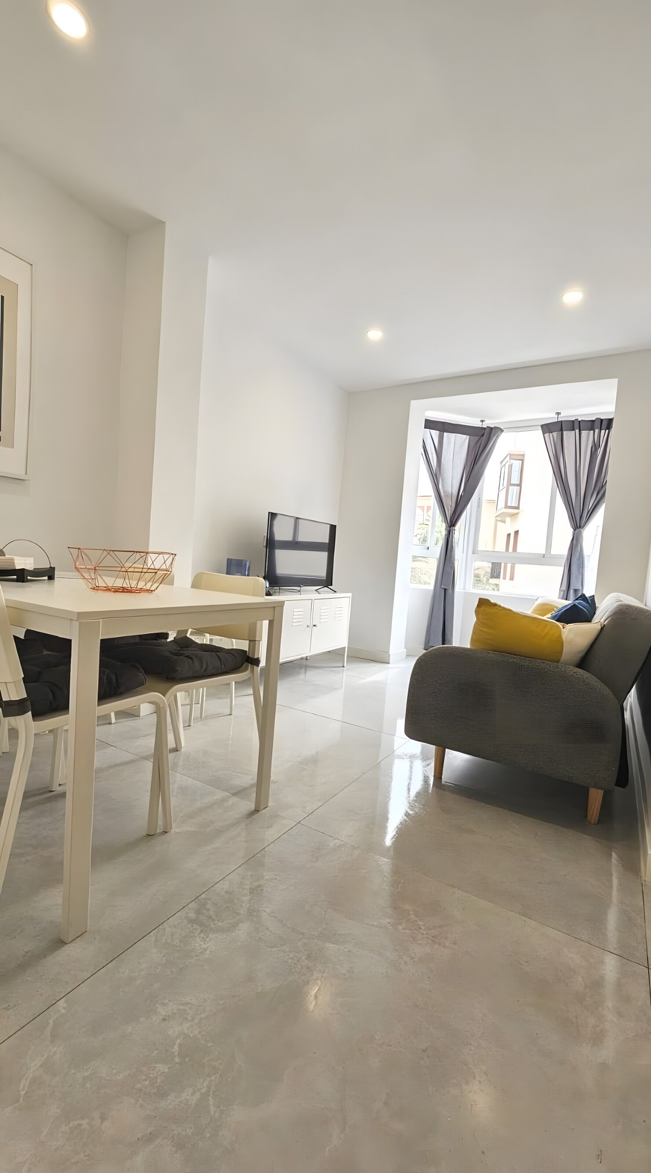 Una sala de estar moderna con comedor, televisor de pantalla plana y sofá con cojines.