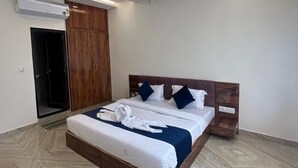 Ein modernes Hotelzimmer mit einem großen Bett, einem Holz-Kopfteil und einem Deckenventilator.