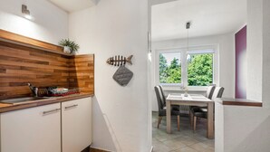 Cocina con armarios de madera, un lavamanos y una ventana con vistas a follaje.