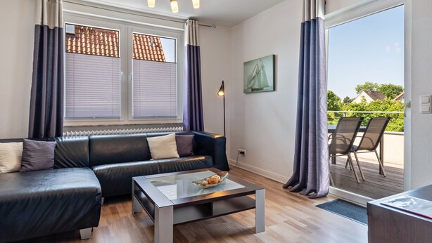 Una sala de estar moderna con un sofá de cuero, una mesa de centro de vidrio y vistas al exterior a través de un ventanal corredero.