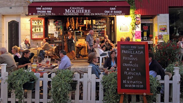 Um restaurante com área externa, uma placa anunciando uma oferta especial e vista para a rua.