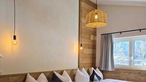 A large bed with a wooden headboard, multiple pillows, and a woven light fixture above it. - Mountain Lodge (Flachau)
