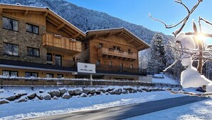 A wooden lodge with a stone facade, named 'Lake View Lodge', set against a snowy mountain backdrop. - Mountain Lodge (Flachau)