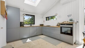 Une cuisine moderne avec des meubles gris, un plan de travail en bois et une lucarne.