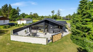 Une maison moderne dotée d’une grande terrasse, d’un patio et d’un mur en pierre.