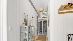 Un couloir avec une vitrine, un banc en bois et une étagère fixée au plafond.