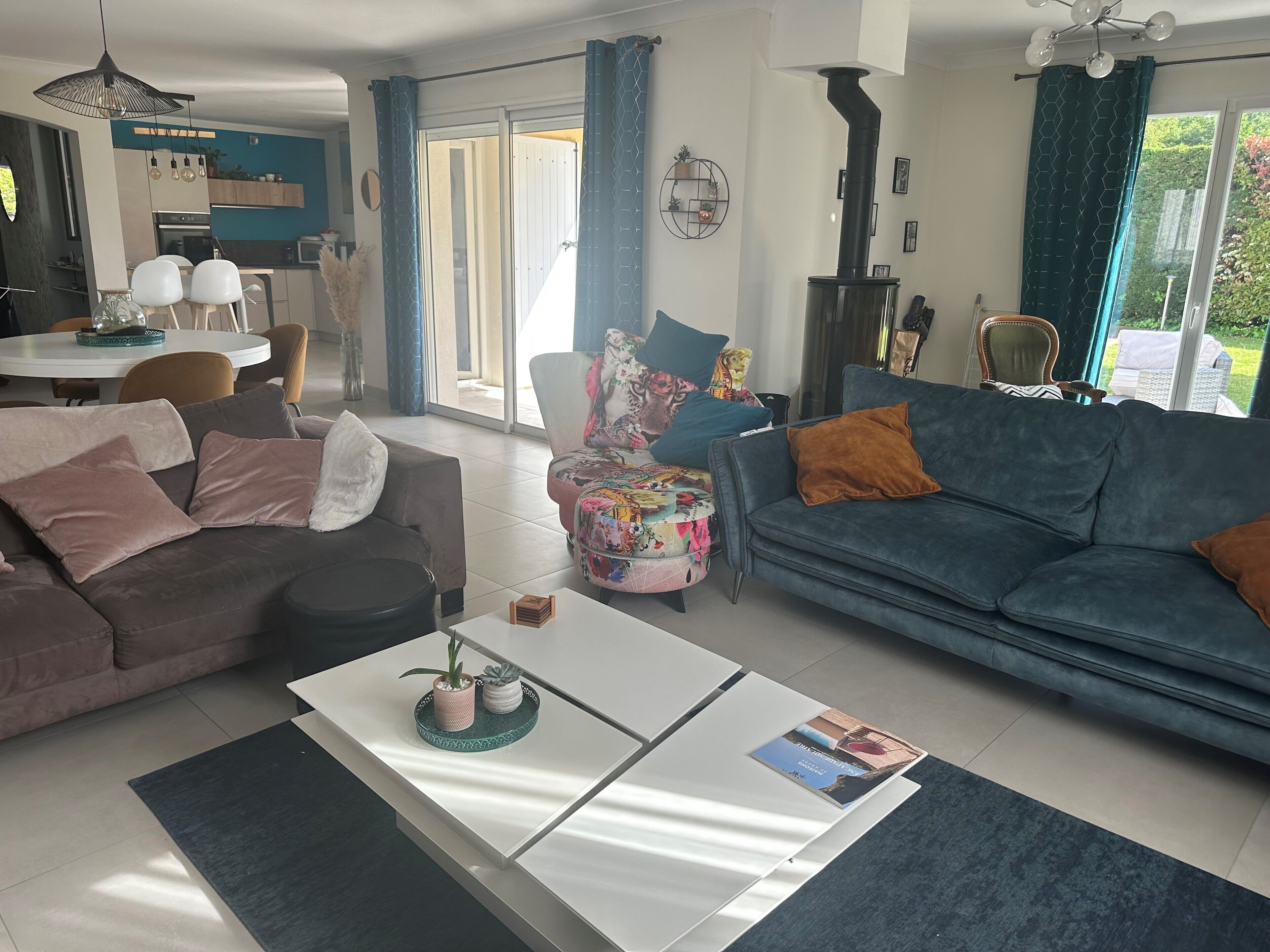 Un salon moderne avec un canapé gris, un canapé bleu et une table basse blanche agrémentée d’objets décoratifs.
