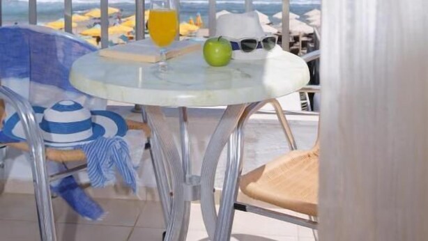 A balcony with a glass table, a green apple, and a glass of orange juice. - Semeli Stalis (Stalida)