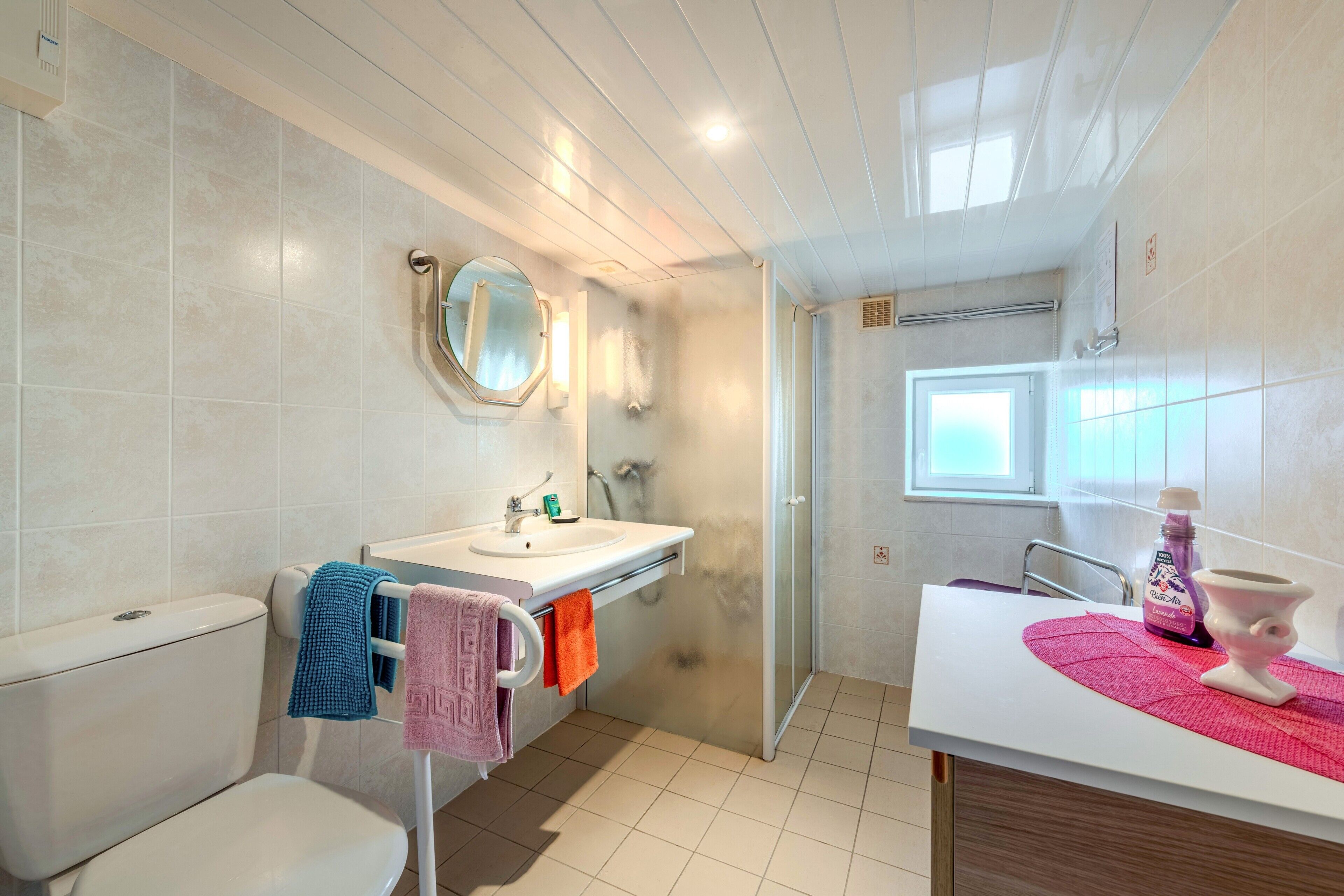 A bathroom with a toilet, sink, mirror, and shower area.