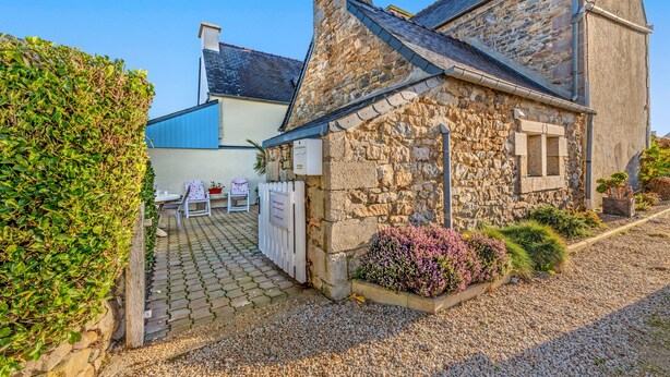 A stone building with a paved driveway, a white fence, and a small garden area with shrubs. - Holiday Home 'Maison De Caractère' with Wi-Fi (Roscoff)