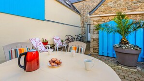 A round table with a red kettle, a plate of pastries, and two white cups. There are striped chairs and a potted plant. - Holiday Home 'Maison De Caractère' with Wi-Fi (Roscoff)