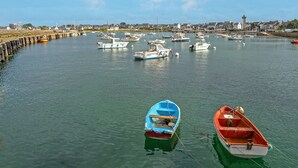 A harbor with multiple boats docked, a lighthouse in the background, and a calm water surface. - Holiday Home 'Maison De Caractère' with Wi-Fi (Roscoff)