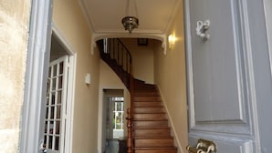A wooden staircase leading to a landing with a door and a light fixture above.