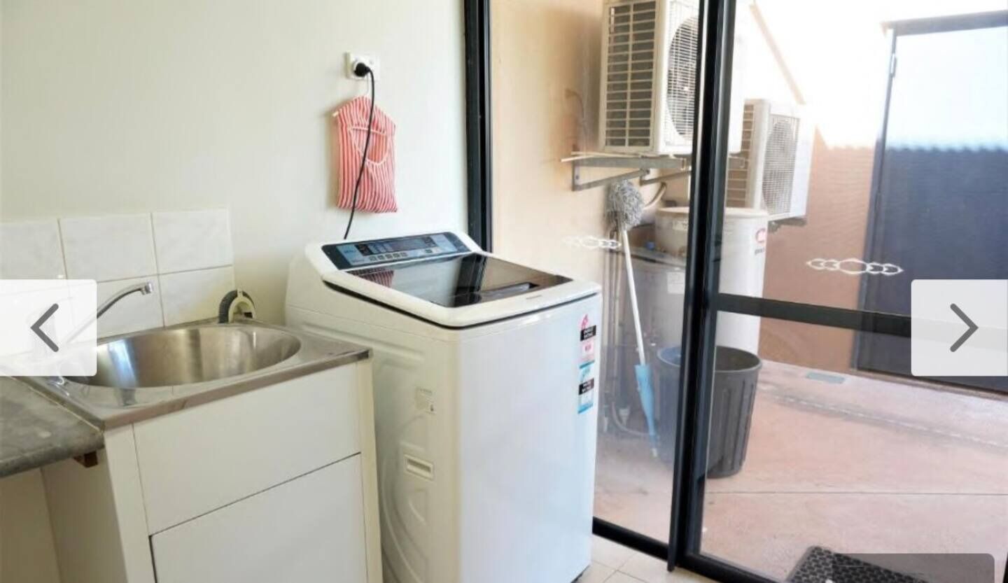 Une cuisine équipée d’un lave-linge, d’un évier et d’une fenêtre donnant sur un patio.