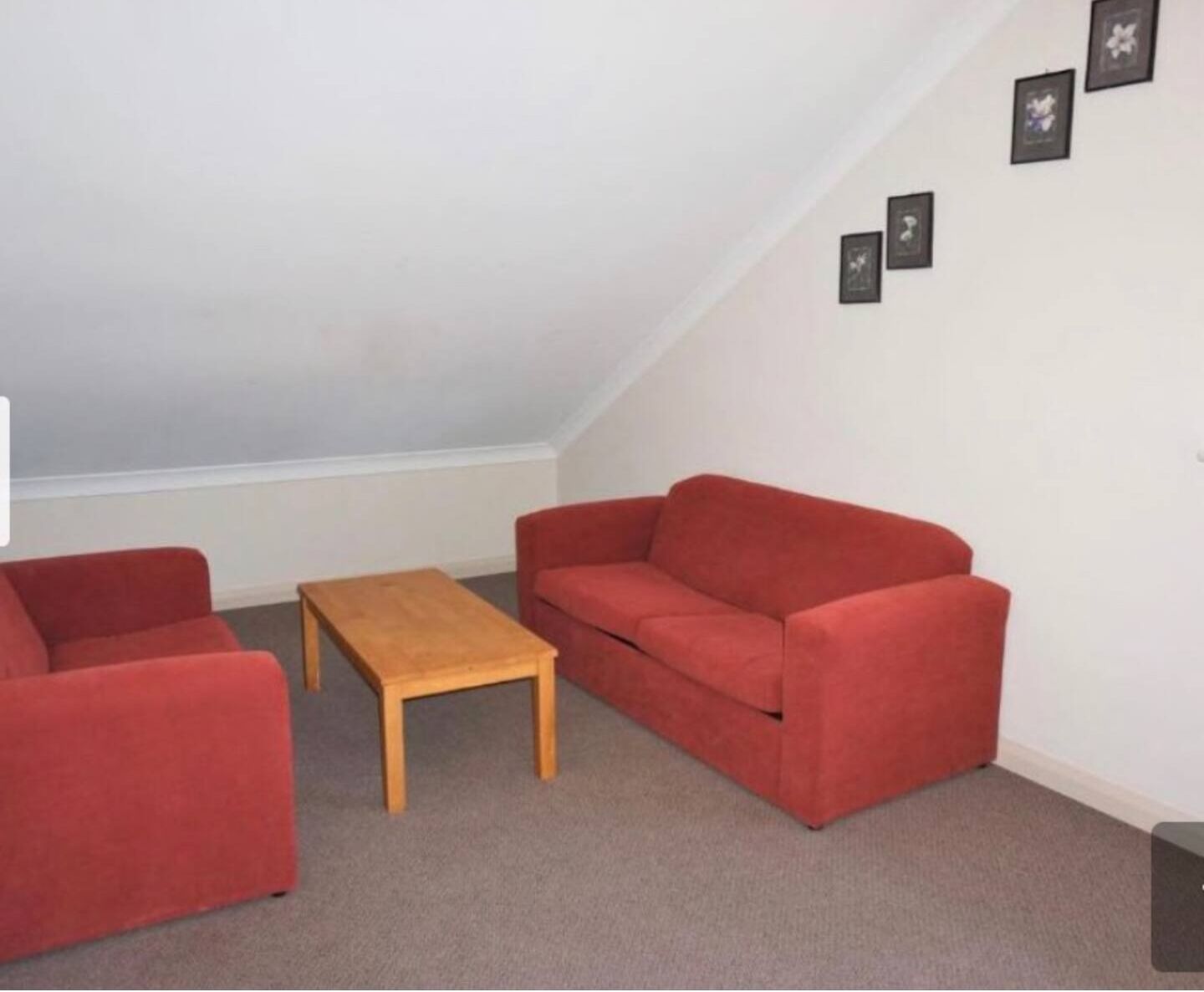 A small, red-furnished room with a wooden coffee table and two red sofas.