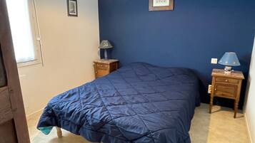 A bedroom with a bed, two bedside tables, a lamp, and a framed picture on the wall.