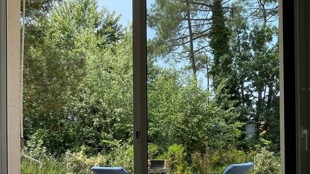 A sliding glass door leading to an outdoor patio with two lounge chairs and a fire pit. - Family House 400m from the Beach - La Grière Plage (La Tranche sur mer)