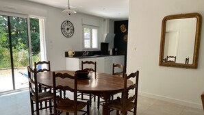 A dining area with a wooden table and chairs, a kitchen in the background, and a large mirror on the wall. - Family House 400m from the Beach - La Grière Plage (La Tranche sur mer)