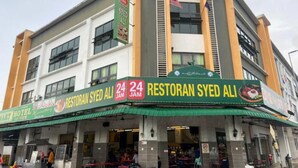 A restaurant named Restoran Syed Ali with a green awning and a sign indicating it is open 24 hours.