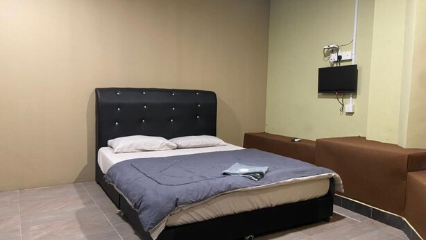 A bedroom with a bed, a television mounted on the wall, and a brown bench.
