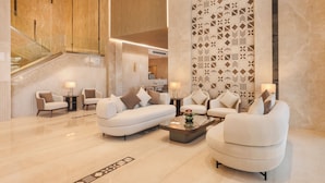 Eine geräumige Lobby mit modernem Design, ausgestattet mit einer großen Sitzecke, Sofas, Sesseln, einem Couchtisch und einer Wand mit Muster.