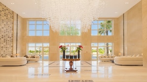 Eine geräumige Lobby mit hoher Decke, großen Fenstern und einer zentral platzierten Blumenkomposition.