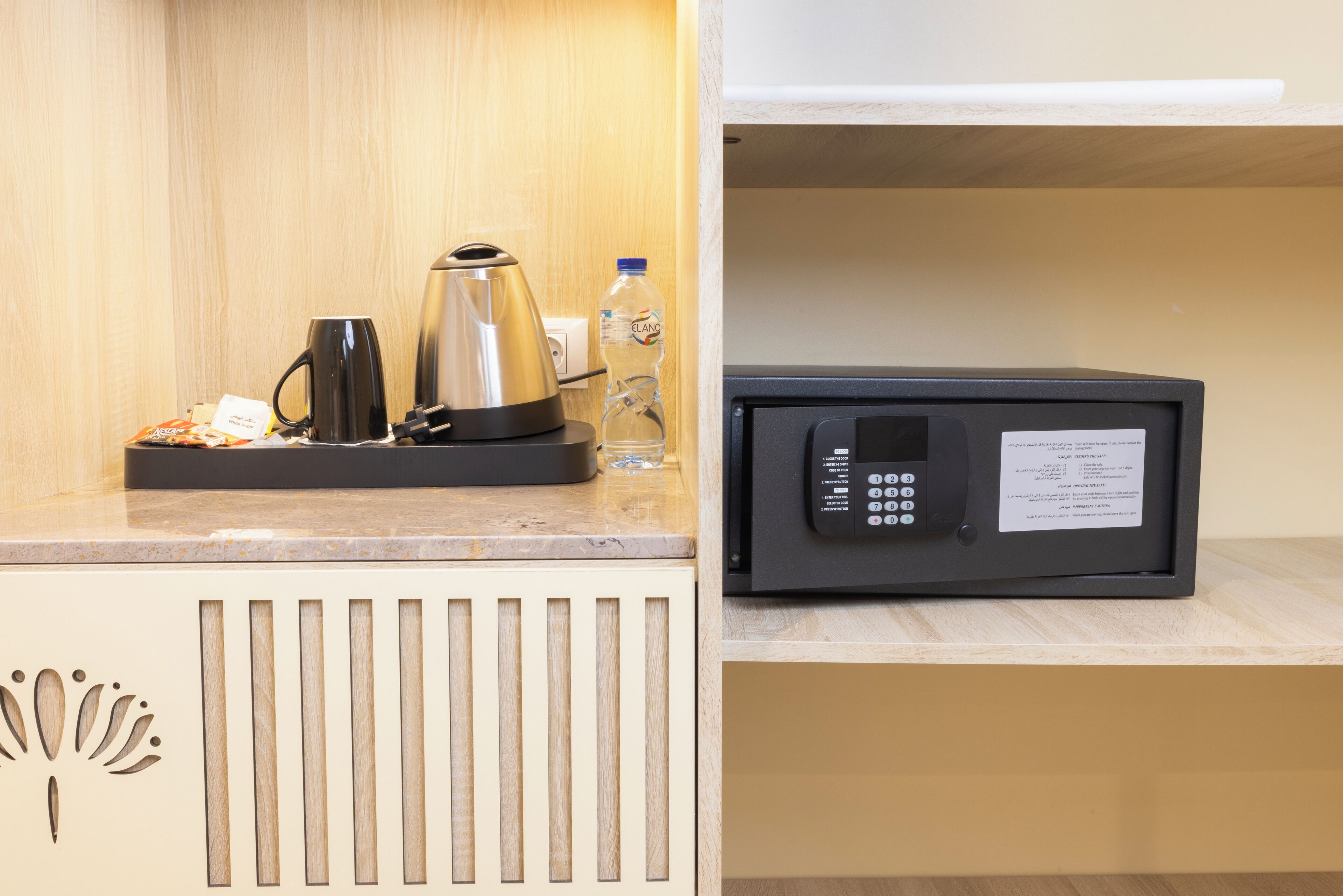 A kitchenette with a coffee maker, a kettle, and a bottle of water on the counter.