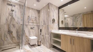 Un baño moderno con ducha de vidrio, inodoro, lavamanos y tocador con espejo.