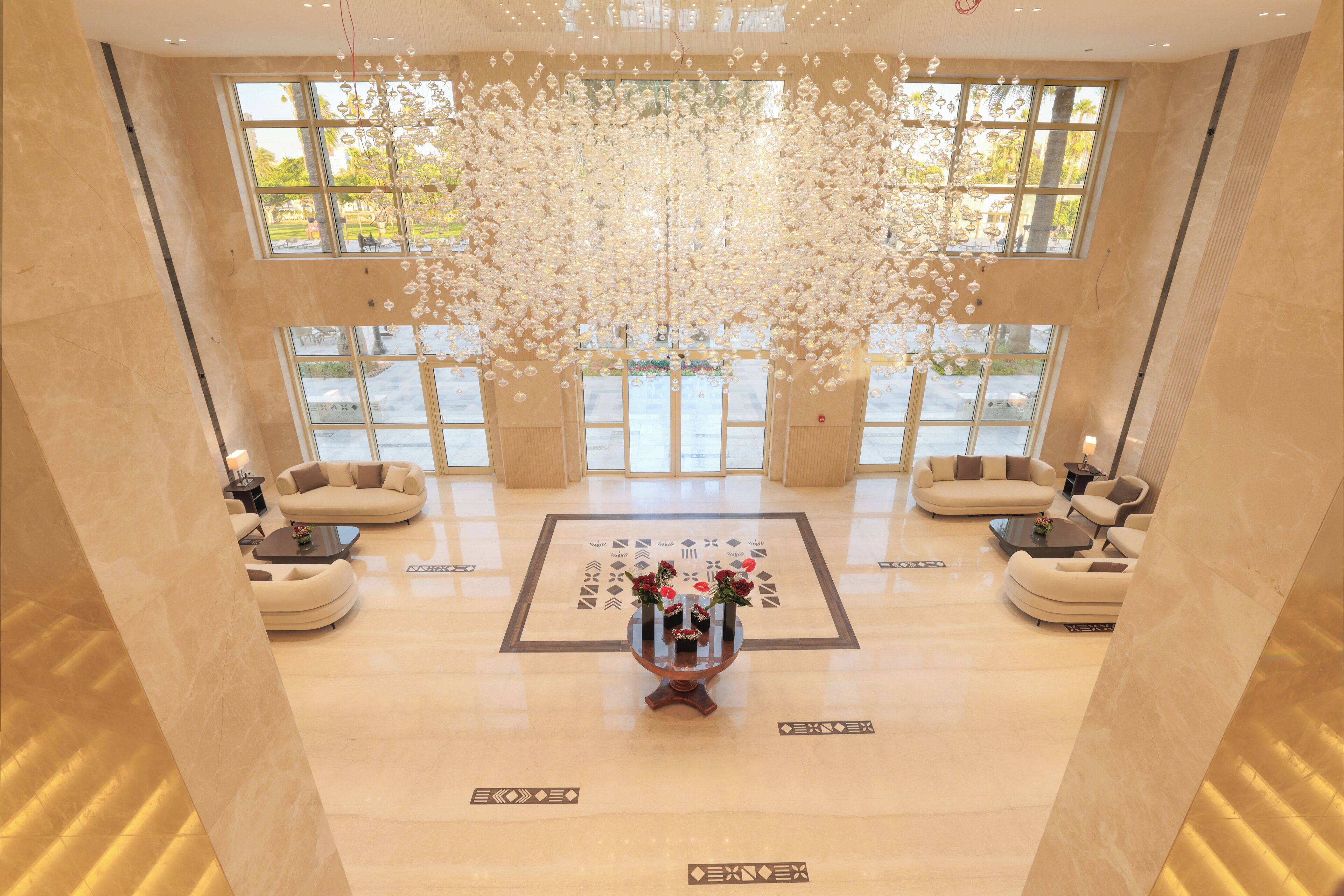 Eine großzügige Lobby mit einem zentralen Couchtisch, Sofas und einer dekorativen Deckeninstallation.