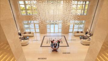 Eine großzügige Lobby mit einem zentralen Couchtisch, Sofas und einer dekorativen Deckeninstallation.