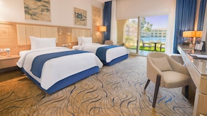 Ein Hotelzimmer mit zwei Betten, einem Schreibtisch und einem Stuhl. Blick auf einen Pool und Palmen.
