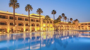 A hotel with a large pool, palm trees, and a classic architectural style. - Helnan Antoniades Palace (Alexandria)