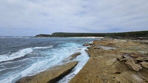Une côte rocheuse où les vagues s’écrasent sur le rivage.