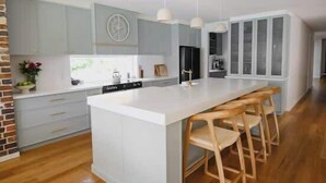 Une cuisine moderne dotée d’un îlot central, de tabourets de bar et de luminaires suspendus.