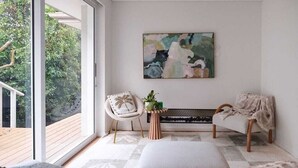 Une pièce avec une grande fenêtre, un banc, une chaise et un tableau accroché au mur.