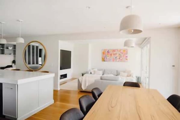 Un salon moderne comprenant une table à manger, des chaises, un canapé et un téléviseur.