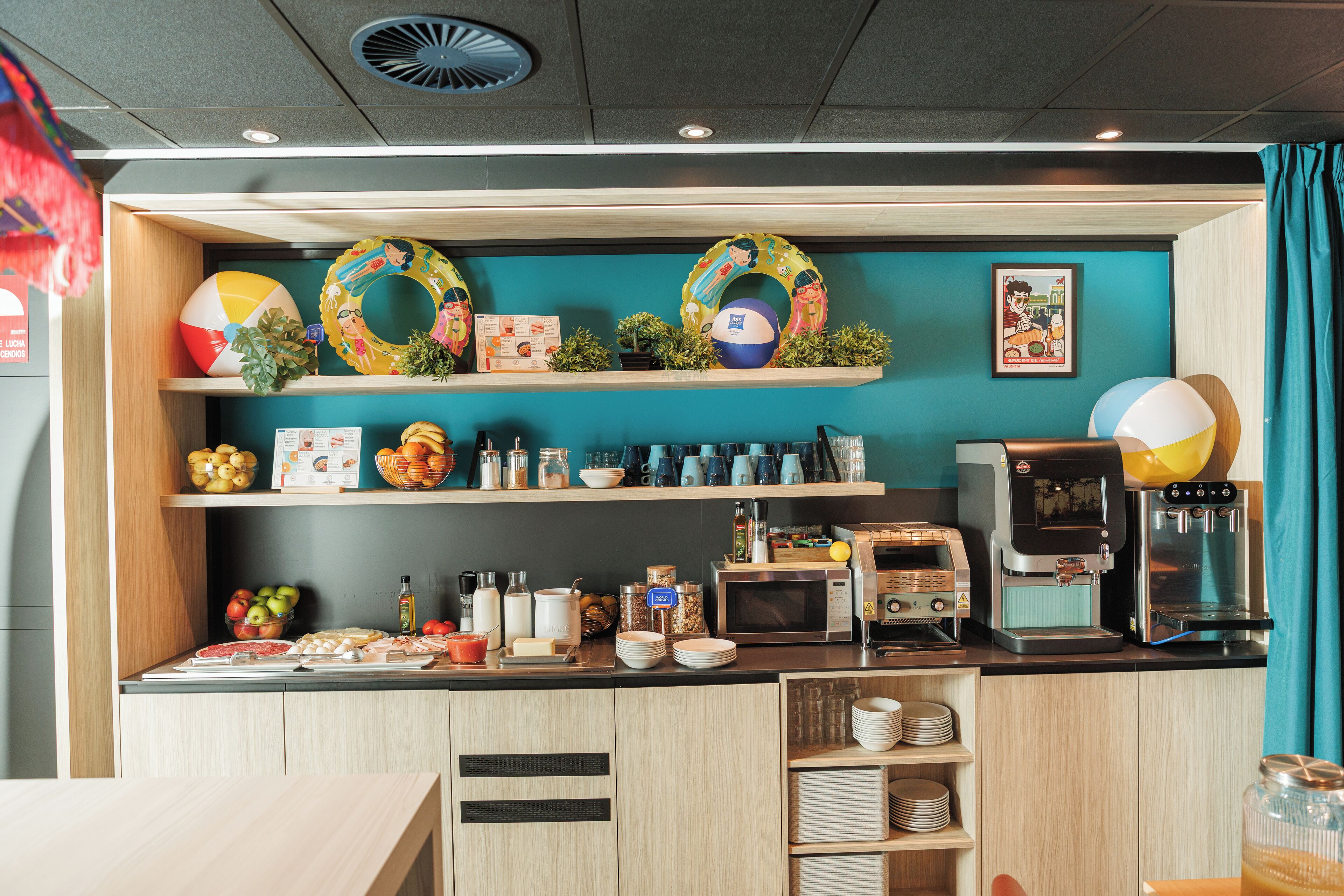 A kitchen area with a coffee machine, microwave, and various food items on shelves.