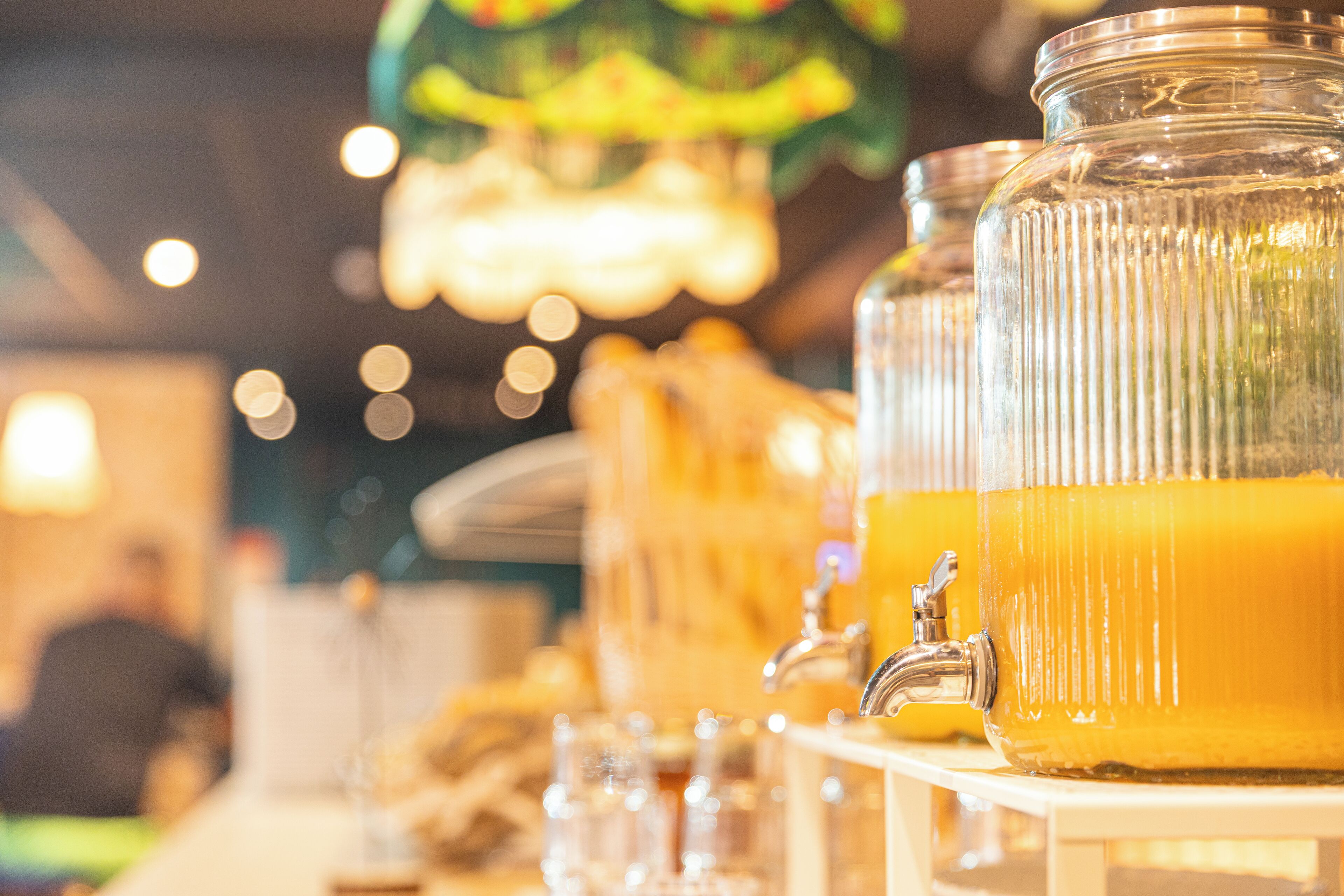 A beverage dispenser with multiple glass containers filled with a yellow liquid, likely juice or punch, and a faucet attached to the dispenser.