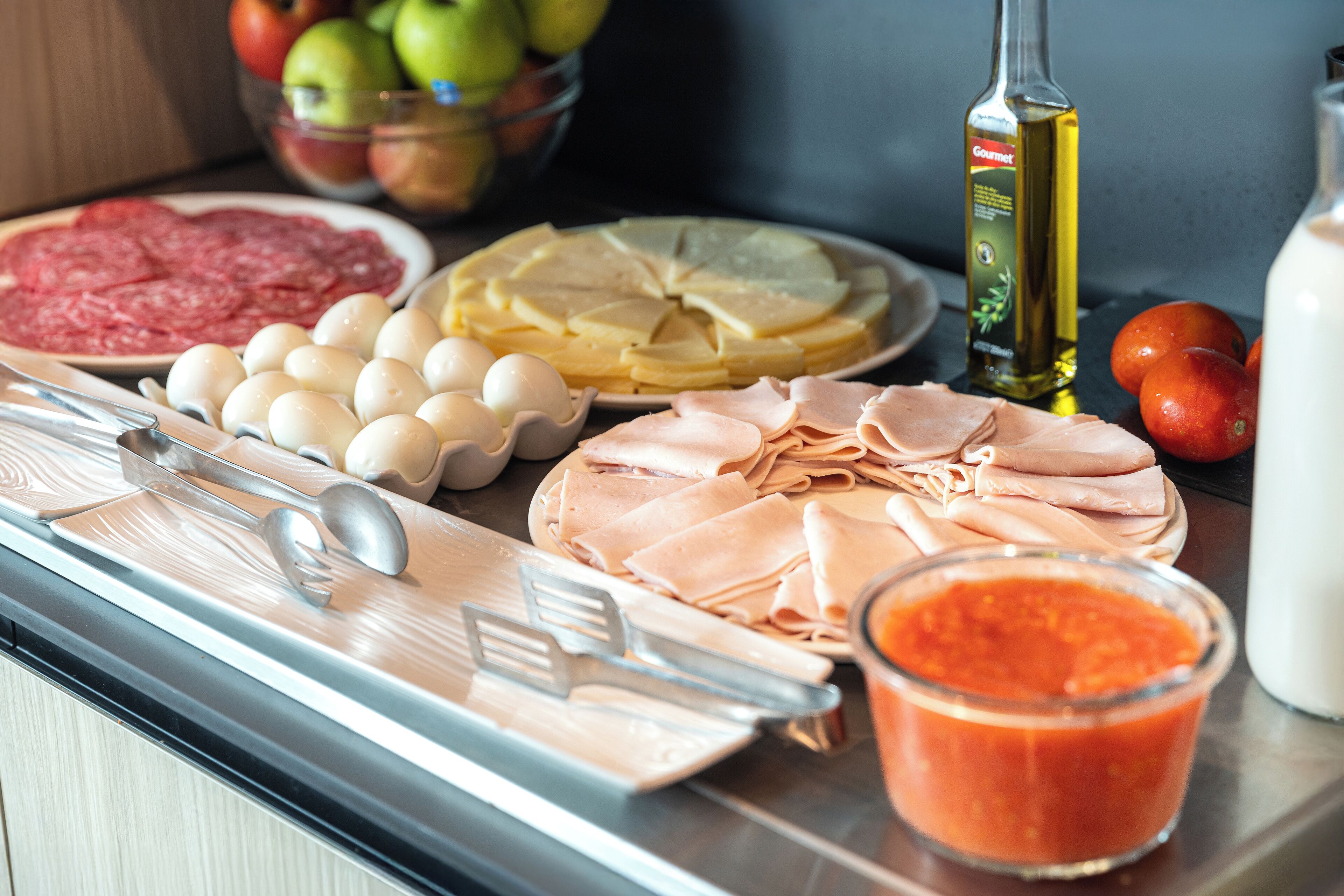 Una encimera de cocina con diversos alimentos, como huevos, carne y un tazón de fruta.