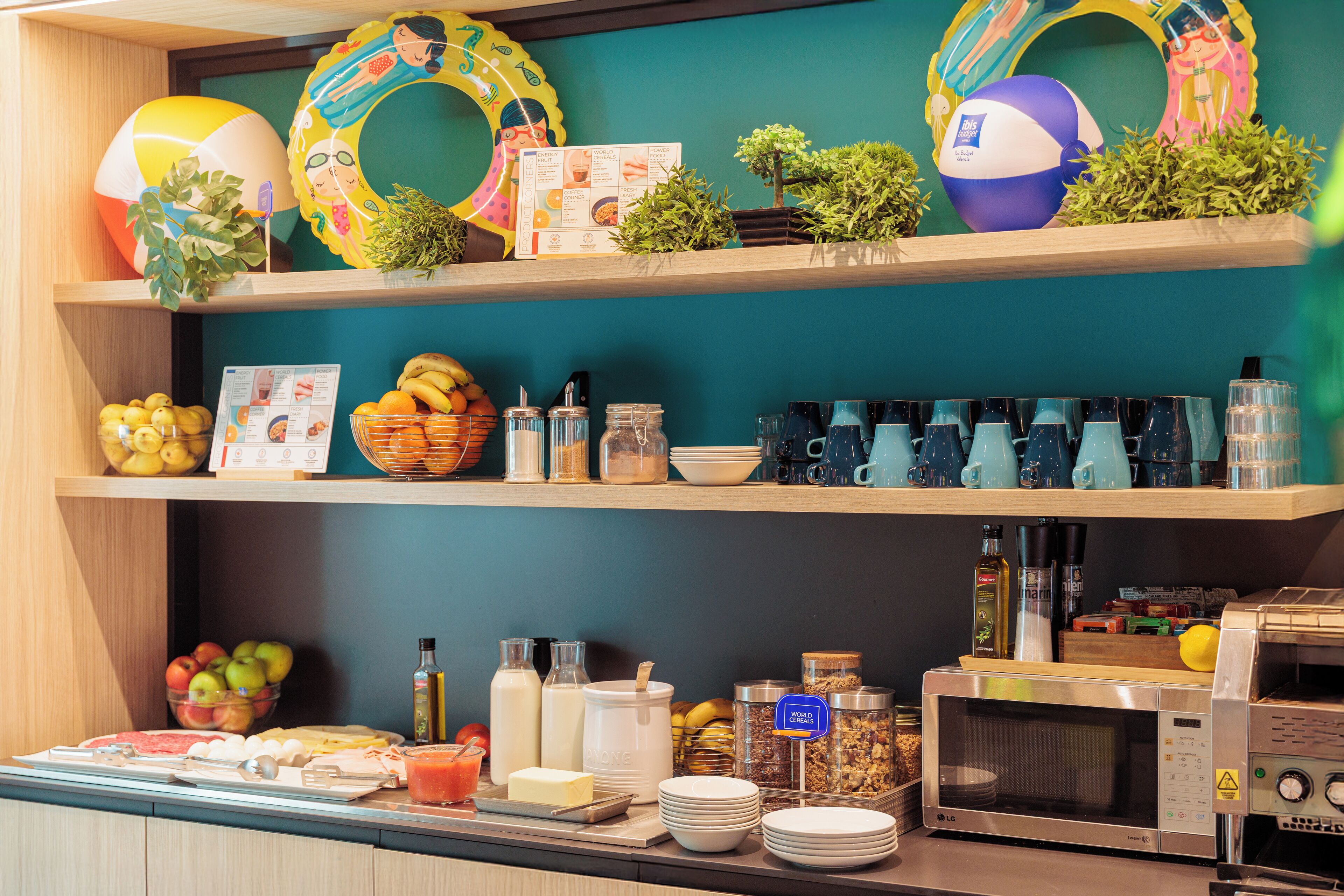 Un bufé de desayuno con diversas opciones de comida, un microondas y adornos con motivos playeros en estantes.