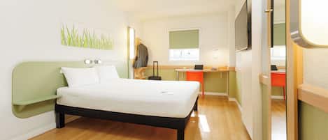 A modern hotel room with a bed, a desk, a chair, a TV, and a window.