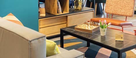 A modern living room with a chessboard, a coffee table, and a sofa with cushions.
