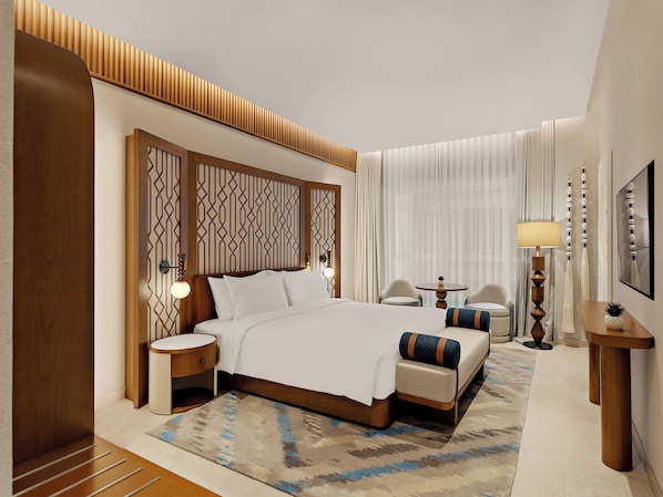 A hotel room with a large bed, bedside tables, a small round table, a lamp, and a mirror.