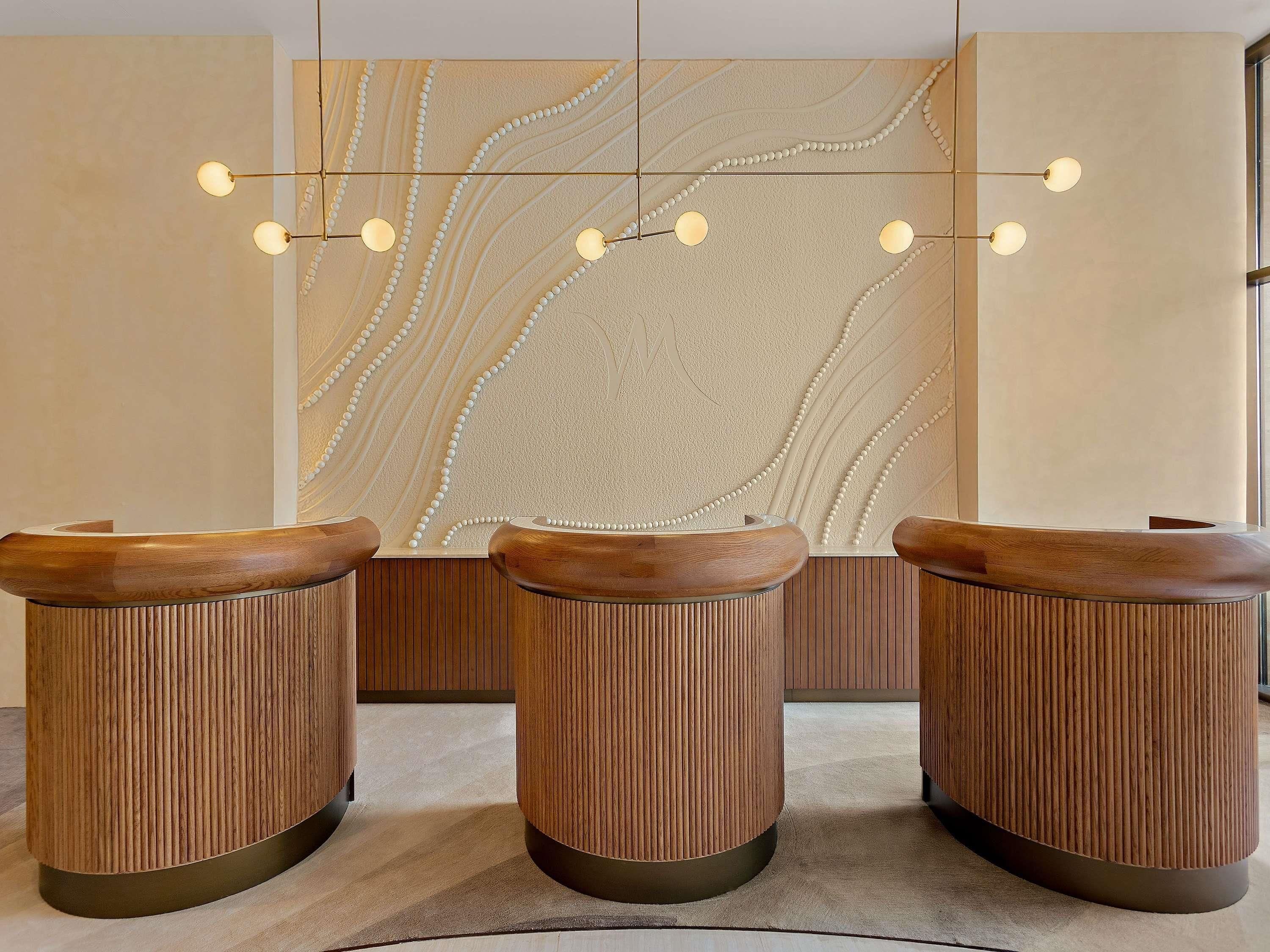 A reception area with three wooden counters and a wall with a textured design.
