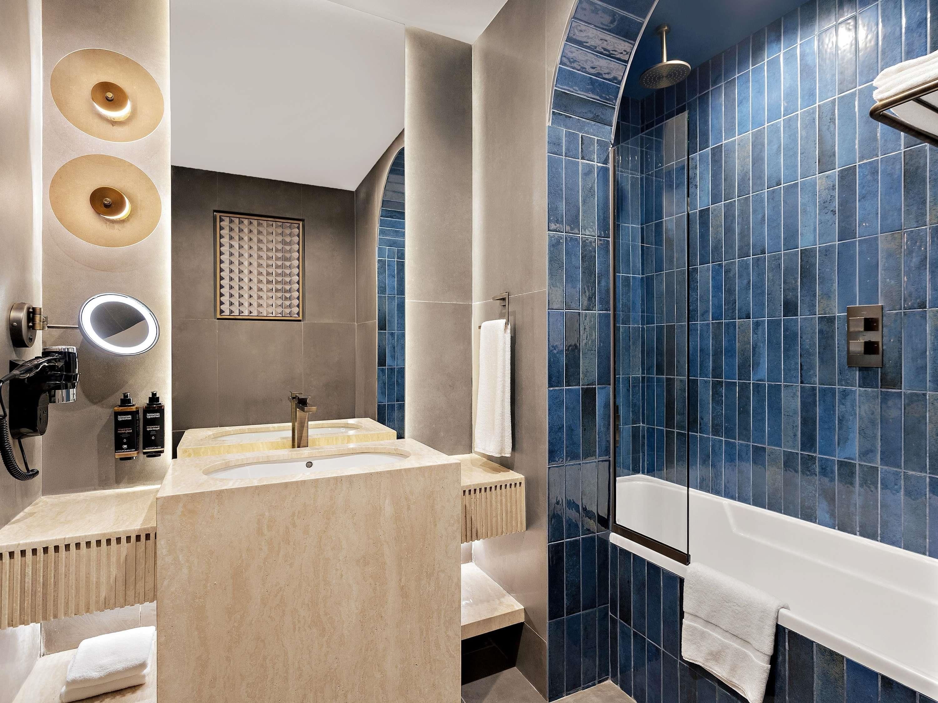 Een moderne badkamer met een wastafel, spiegel en douche.