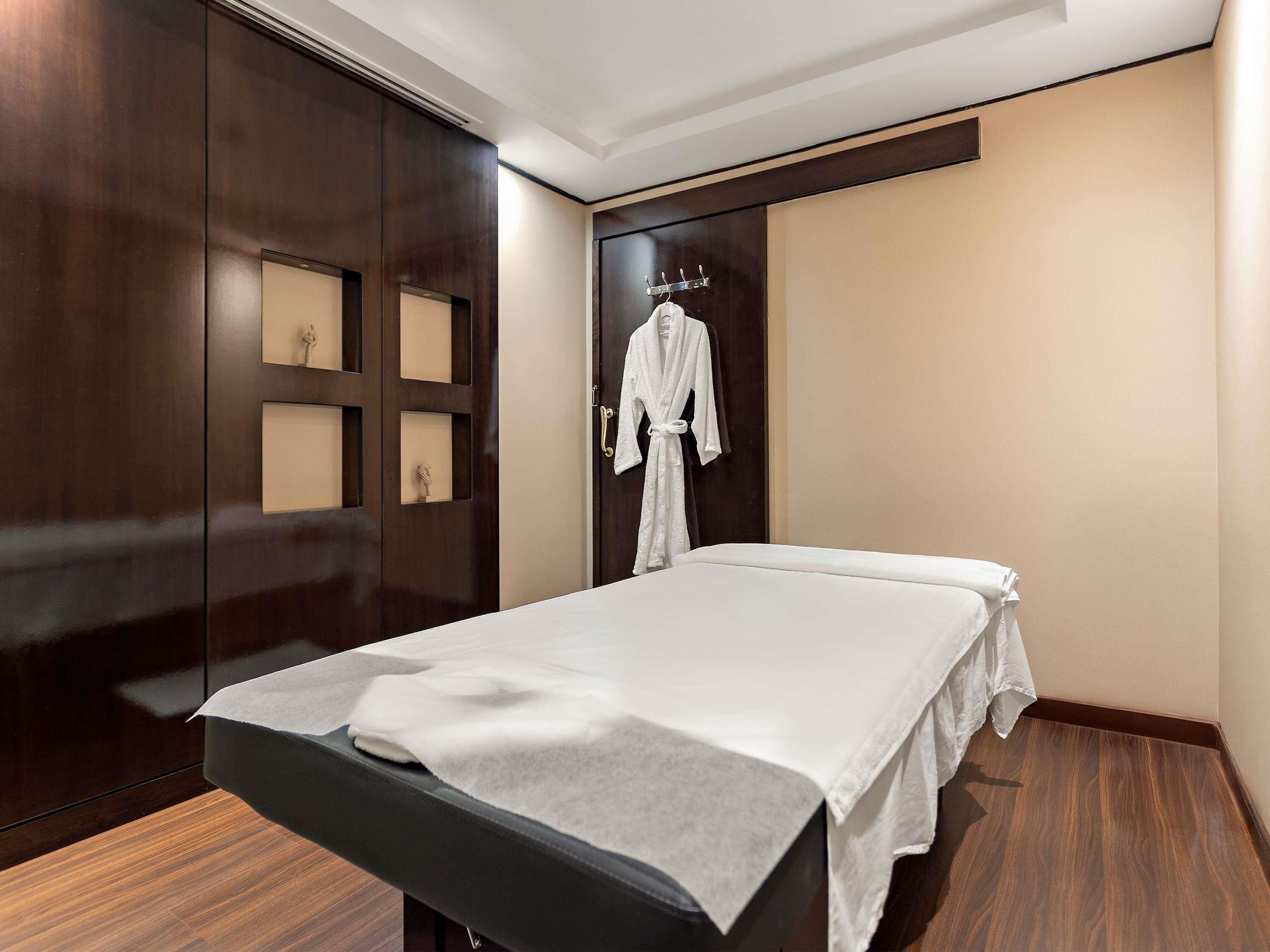Ein Hotelzimmer mit einem Bett, einem an der Wand hängenden Bademantel und einem Holzschrank.