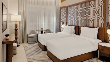 Une chambre d’hôtel avec un grand lit, deux tables de chevet, une chaise, une petite table et une lampe.