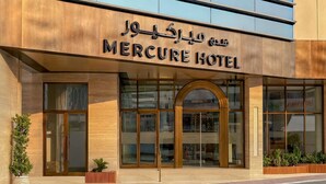 Het exterieur van Hotel Mercure met een moderne gevel, grote glasramen en een opvallende ingang.
