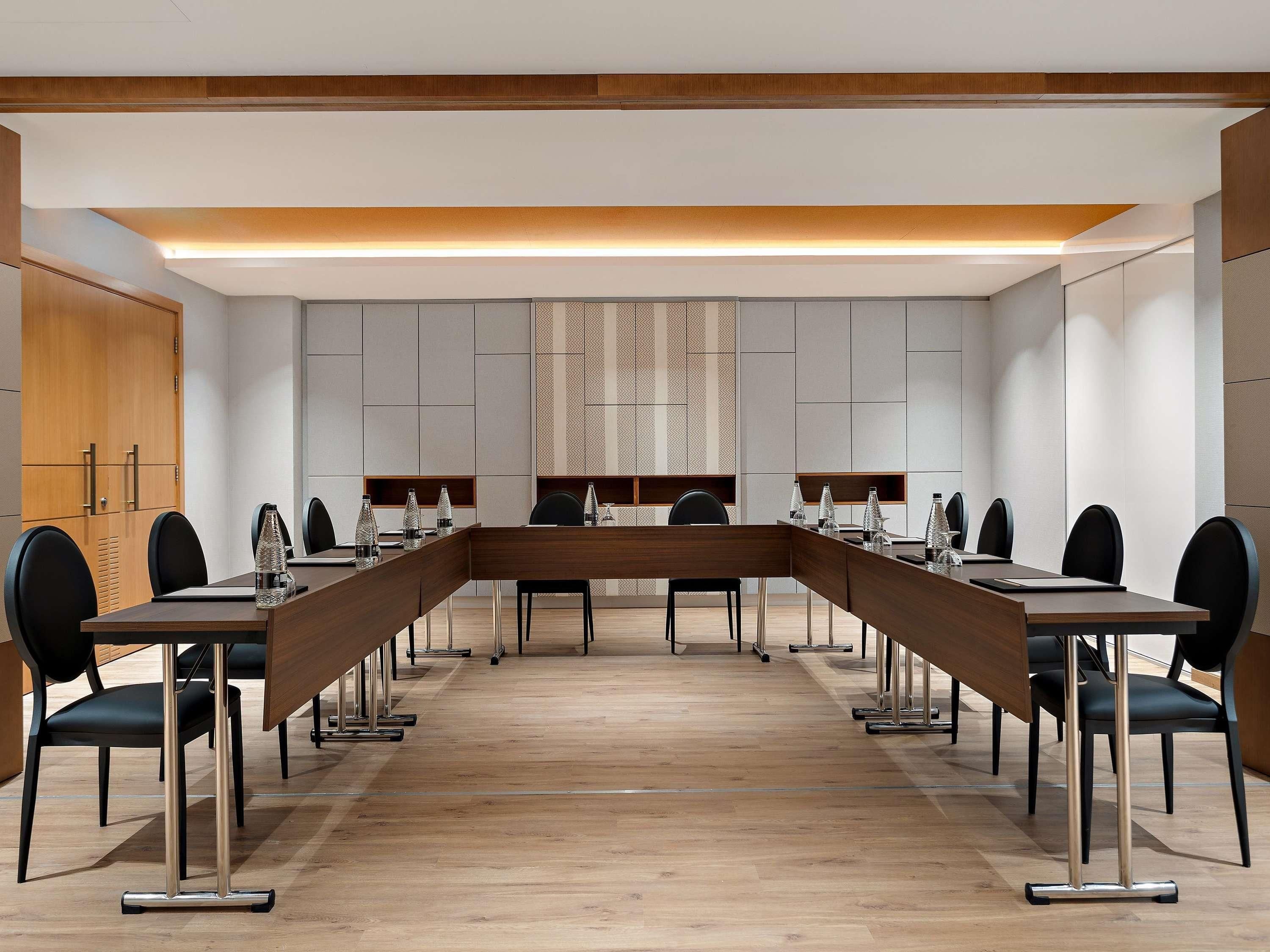 A conference room with a long table, chairs, and a wooden cabinet.